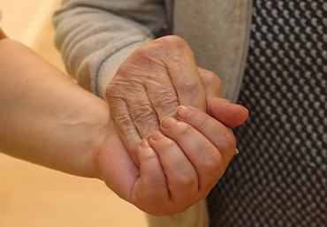 Es sind Haende zweier Personen zu sehen. Eine Person reicht der anderen Person die Hand zur Hilfe.